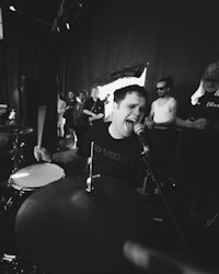 a black and white photo of a man playing drums in front of a crowd